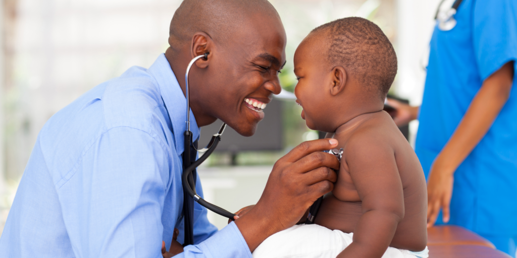 African American, Male Doctor Examining an African American Toddler. Both are laughing.